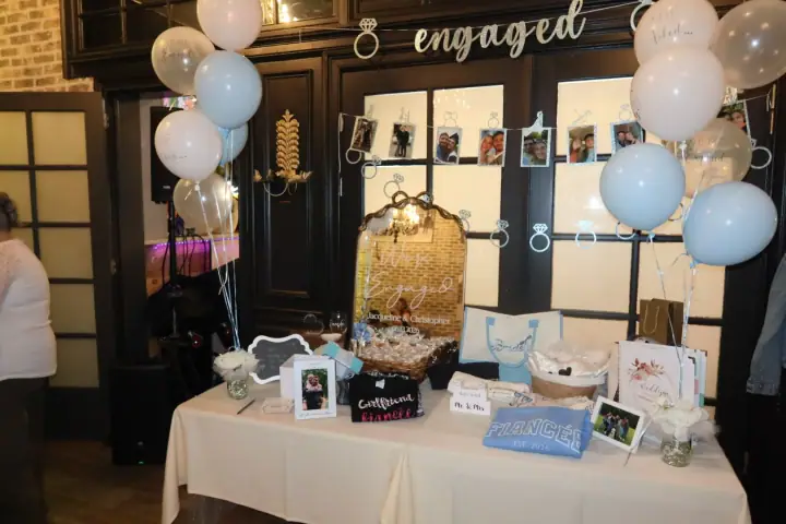 Engagement party display with balloons, photos, flowers, and gifts