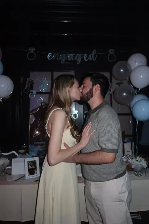 Christopher and Jacqueline kissing in front of the engagement display