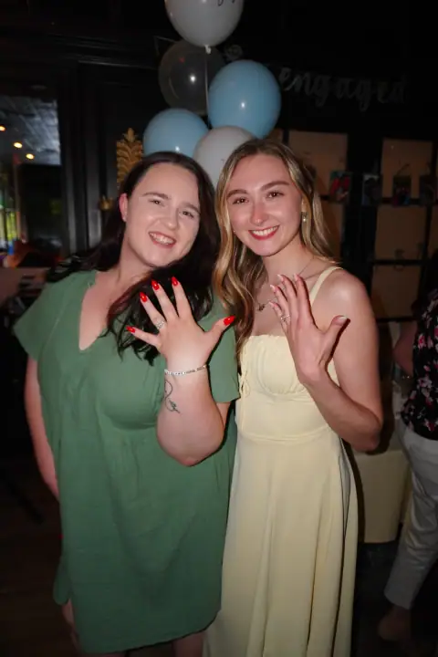 Jacqueline and a friend smiling and showing their rings