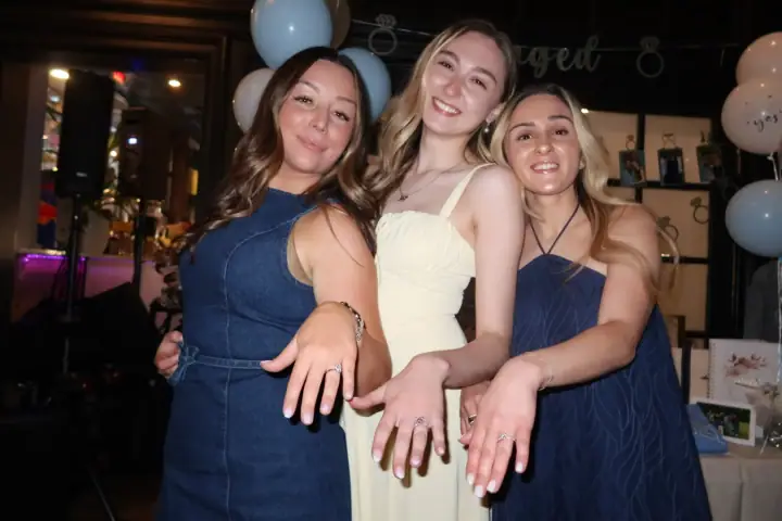 Jacqueline and two friends leaning together and showing their rings