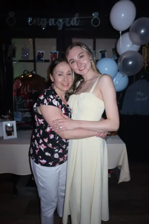 Jacqueline hugging a family member in front of the engagement display