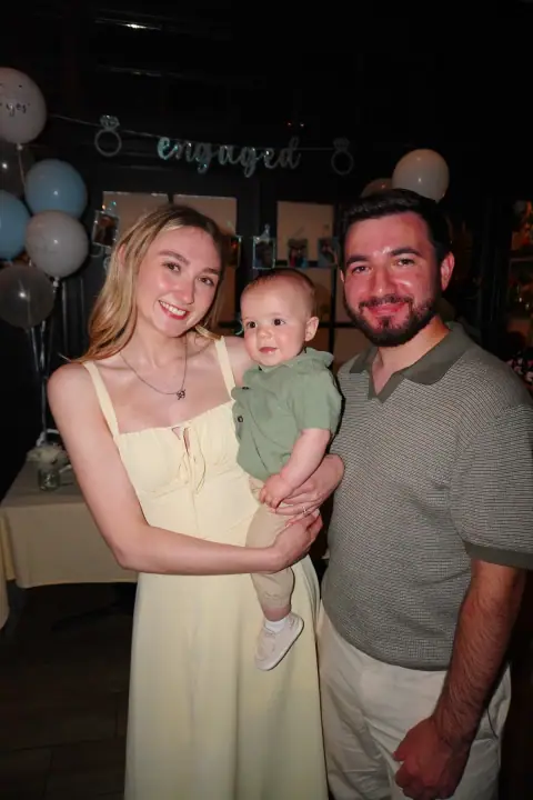 Christopher and Jacqueline smiling while Jacqueline holds a baby