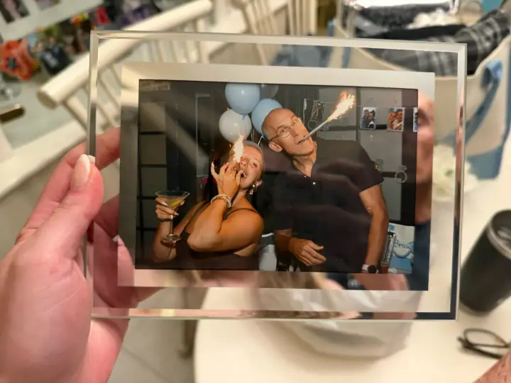 A party instant photo held above a collection of printed memories