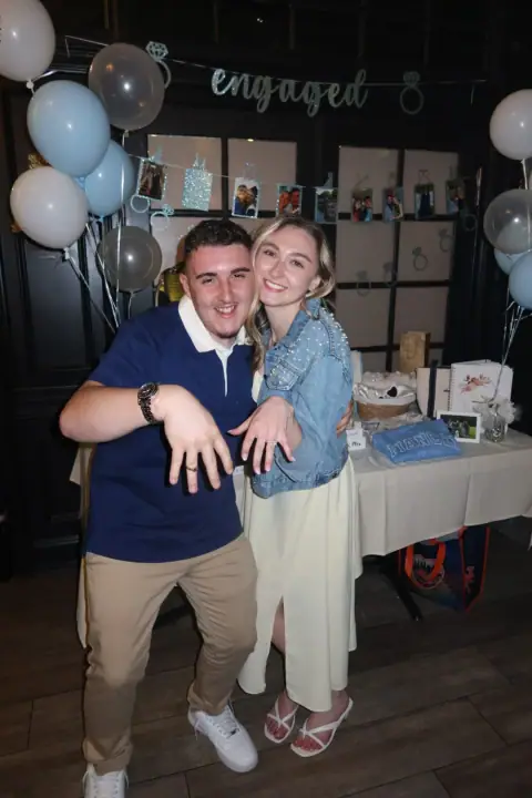Jacqueline posing with a friend as they show their rings
