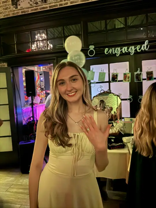 Jacqueline smiling and showing her engagement ring